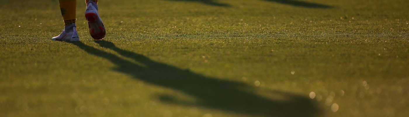 Un futbolista camina sobre el césped