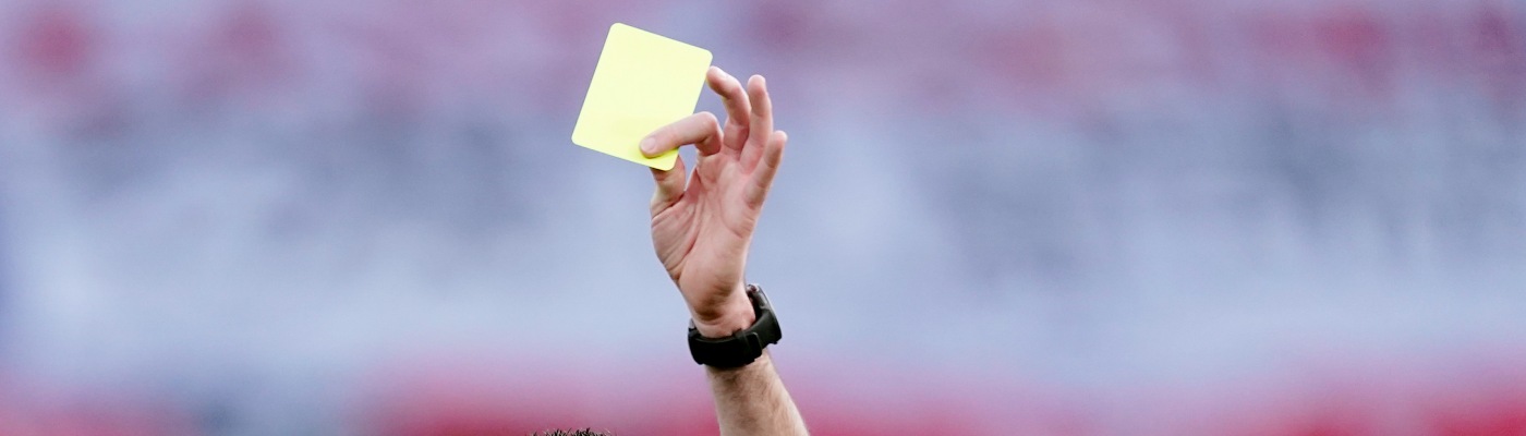Un colegiado muestra una cartulina amarilla durante un partido