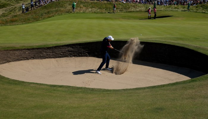 Un golfista intenta sacar la pelota de un bunker